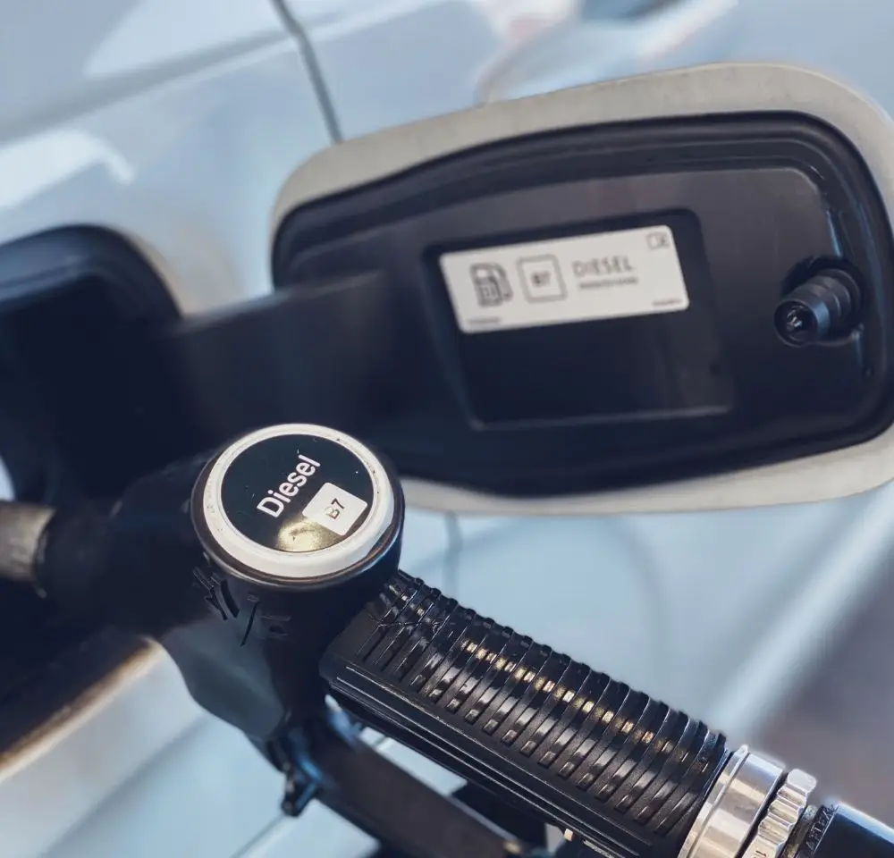 A close-up of a diesel fuel pump nozzle inserted into a vehicle’s fuel tank, with the fuel cap open and a label inside indicating diesel fuel use, highlights the importance of a Misfuelling Cover for private vehicles.