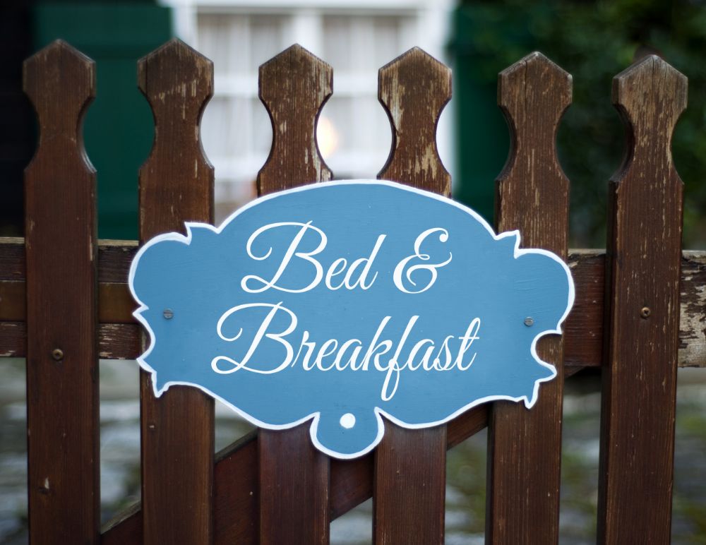 blue bed and breakfast sign on a wooden fence thats painted brown